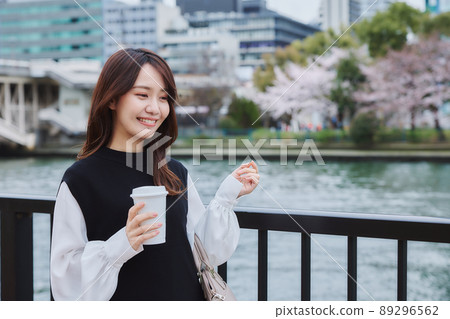 A woman with a coffee on the riverside promenade 89296562