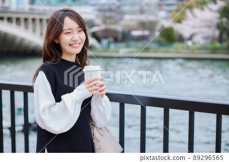 A woman with a coffee on the riverside promenade 89296565