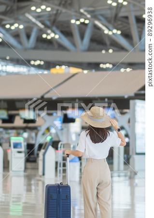 Young woman hand holding luggage handle before checking flight time in airport, Transport, insurance, travel and vacation concepts 89296938