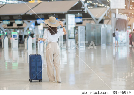 Young woman hand holding luggage handle before checking flight time in airport, Transport, insurance, travel and vacation concepts 89296939