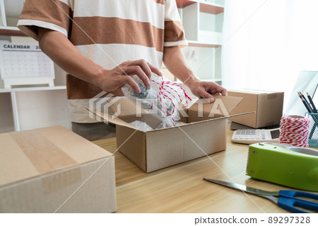 Online shopping concept the shop dealer wrapping his product and putting it into the package Online shopping concept the shop dealer wrapping his product and putting it into the package 89297328