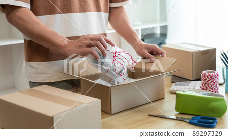 Online shopping concept the shop dealer wrapping his product and putting it into the package Online shopping concept the shop dealer wrapping his product and putting it into the package 89297329