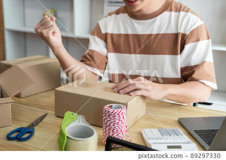 Online shopping concept the online salesperson having cheerful facial expression while setting his goods into the box Online shopping concept the online salesperson having cheerful facial expression while setting his goods into the box 89297330