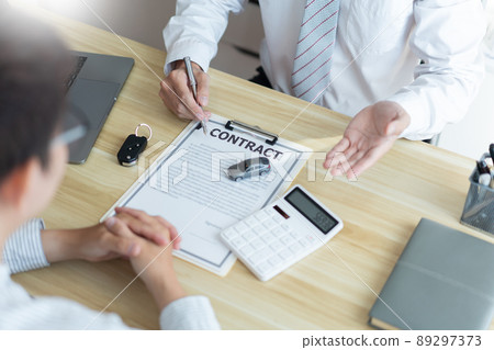 Insurance concept the car salesman describing the agreement on car contract to his customer 89297373