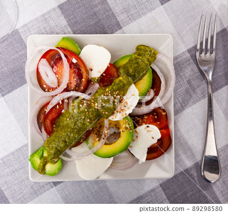 Salad of mozzarella, tomatoes, onion and avocado with pesto and sesame Salad of mozzarella, tomatoes, onion and avocado with pesto and sesame 89298580