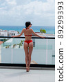 Summer holidays in luxury hotel, woman relaxing near beautiful rooftop swimming pool. Sexy girl wearink bikini enjoy ocean view. Back view, without face 89299393