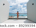 Happy woman beside a rooftop pool with a beautiful city and ocean view on background 89299394