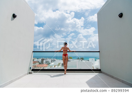Happy woman beside a rooftop pool with a beautiful city and ocean view on background Happy woman beside a rooftop pool with a beautiful city and ocean view on background 89299394