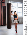 Photo shoot for a young athlete in the interior of a boxing gym with gloves and bags 89299396