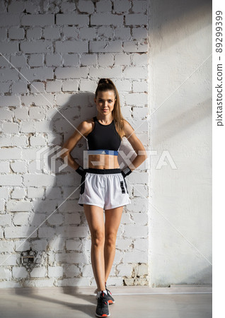 A young female athlete with a perfect body and abs is preparing for training in the early morning 89299399