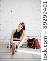 A young girl got tired during boxing training and sat down against the wall to rest and drink 89299401