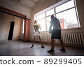 Female boxer practicing hits with her personal trainer in a boxing studio. 89299405