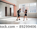 An attractive young boxer teaches his girlfriend boxing techniques in a loft equipped for boxing training 89299406