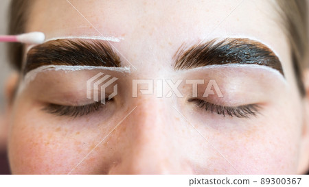The master paints the eyebrows of a woman. The master paints the eyebrows of a woman. 89300367