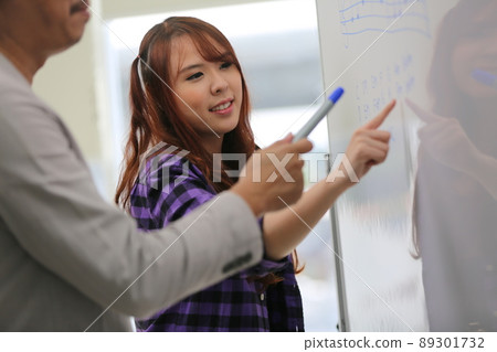 Tutor with cheerful young woman student teaching sound phonetic note on white board. 89301732