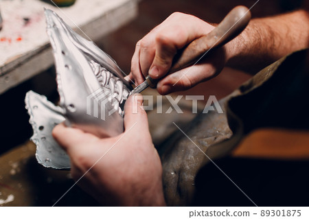 Artisan crafts man create mask based on plaster cast. Gypsum mold and plastic mask sculpting cutting knife Artisan crafts man create mask based on plaster cast. Gypsum mold and plastic mask sculpting cutting knife 89301875