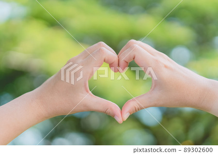 Female hands heart shape on nature bokeh sun light flare and blur leaf abstract background. Copy space of happy love and freedom concept. Vintage tone filter color style. 89302600