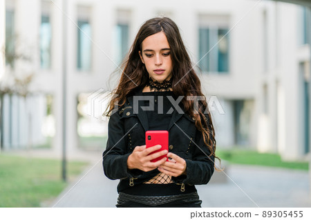 Young woman in black using her phone outside Young woman in black using her phone outside 89305455