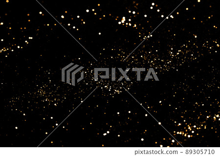 Black festive background. Abstract scattering of gold sparkles on black. Holiday backdrop, selective focus Black festive background. Abstract scattering of gold sparkles on black. Holiday backdrop, selective focus 89305710