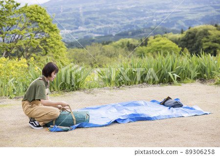 一個年輕女子在搭帳篷前舖一張藍色床單 Solo Can Solo Camper 89306258