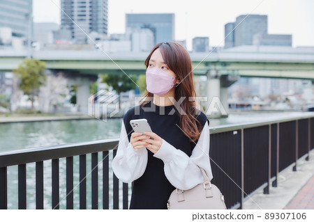 A woman walking along the river promenade while looking at the map app 89307106