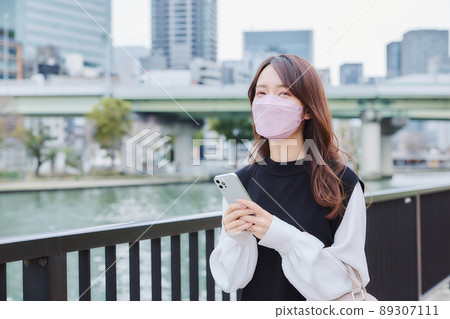 A woman walking along the river promenade while looking at the map app A woman walking along the river promenade while looking at the map app 89307111