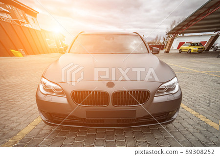 Predatory car headlight with blue lights and hood of powerful grey blue car sports car with matte grey paint and wheel with blue disc Predatory car headlight with blue lights and hood of powerful grey blue car sports car with matte grey paint and wheel with blue disc 89308252