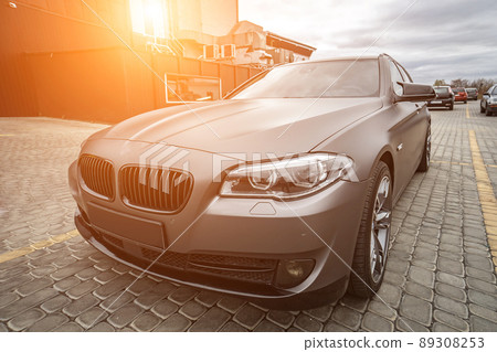 Predatory car headlight with blue lights and hood of powerful grey blue car sports car with matte grey paint and wheel with blue disc 89308253