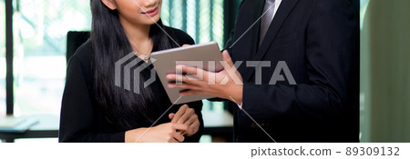 Young asian business team man and woman standing and talking about marketing on tablet. 89309132