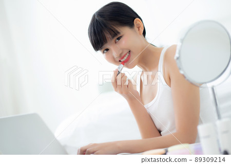 Beauty of young asian woman with learning makeup with lipstick on mouth watching laptop. 89309214