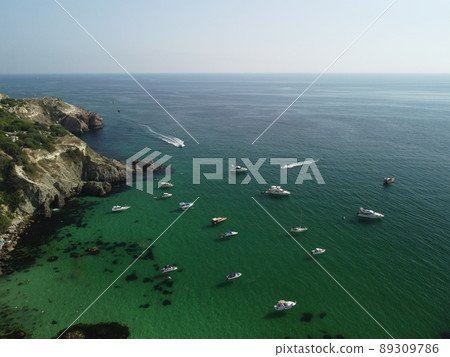 Aerial panoramic view of seascape with crystal clear azure sea and rocky shores. Yachts in a beautiful lagoon on backdrop of rocks. The concept of an ideal destination for summer travel and vacation. Aerial panoramic view of seascape with crystal clear azure sea and rocky shores. Yachts in a beautiful lagoon on backdrop of rocks. The concept of an ideal destination for summer travel and vacation. 89309786