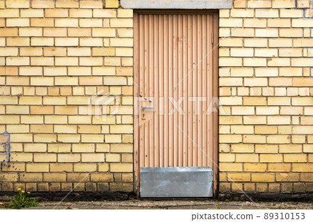 Old wooden door on a yellow  brick wall 89310153