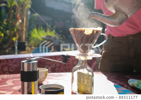 Drip brewing coffee by paper filtered on table morning outdoor Drip brewing coffee by paper filtered on table morning outdoor 89311177