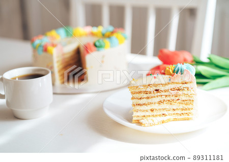 Piece of cake on white plate next to flowers and coffee Piece of cake on white plate next to flowers and coffee 89311181