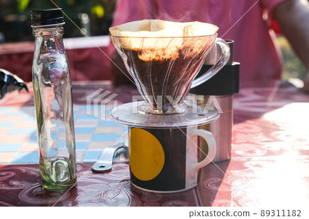 Drip brewing coffee by paper filtered on table morning outdoor Drip brewing coffee by paper filtered on table morning outdoor 89311182