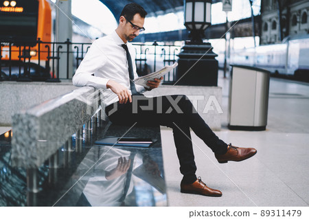 Side view of confident businessman in spectacles for eyes protection reading finance newspaper 89311479