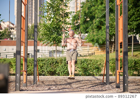 A man in shorts having a workout on a sports ground in the park 89312267