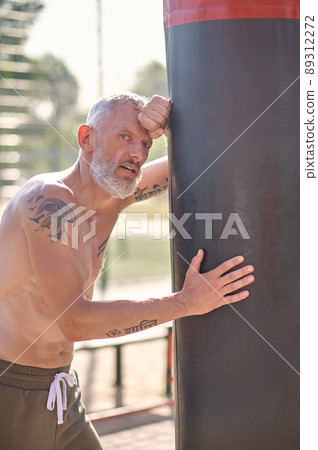 A man with a tattoo on a shoulder resting after boxing workout 89312272