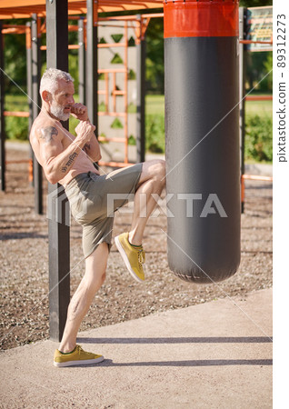 A mature gray-haired man exercising in the park 89312273