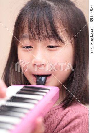 Girl playing keyboard harmonica 89314985