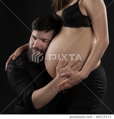 a young man with a beard listens to the big belly of his pregnant wife, portrait, close-up a young man with a beard listens to the big belly of his pregnant wife, portrait, close-up 89315571