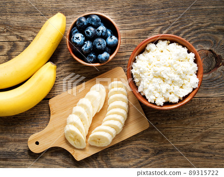 Brown wooden Bowl of homemade curd with banana, jam, blueberries Brown wooden Bowl of homemade curd with banana, jam, blueberries 89315722