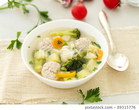 bowl of soup, a cup of broth and vegetables, meatballs made of turkey and chicken, side view bowl of soup, a cup of broth and vegetables, meatballs made of turkey and chicken, side view 89315776