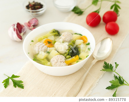 bowl of soup, a cup of broth and vegetables, meatballs made of turkey and chicken, side view 89315778