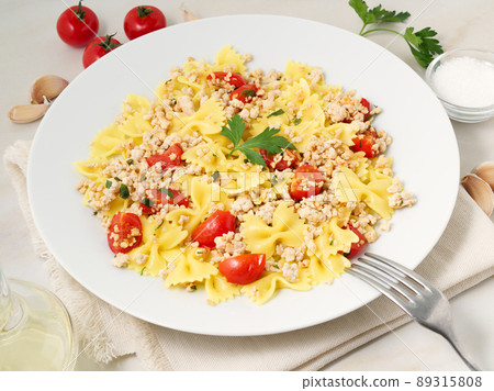 farfalle pasta with tomatoes, chiken meat, parsley on white stone background, low-calorie diet, side view 89315808
