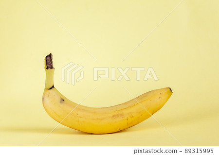 fresh banana with damaged places against yellow background, selective focus, monochrome color 89315995