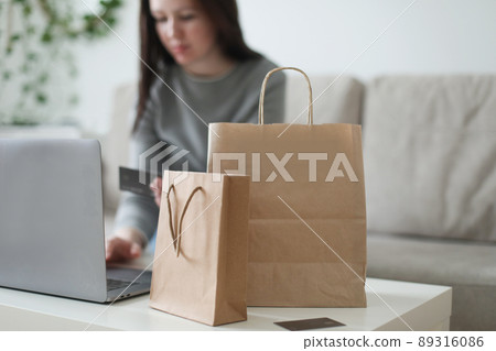 Young woman holding credit card and using laptop at home. Paying online, home shopping, internet banking, electronic store concept 89316086