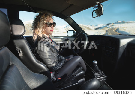 Portrait of a stylish attractive Caucasian young woman getting out of a retro sports car in the mountains at sunset. Travel concept copy space Portrait of a stylish attractive Caucasian young woman getting out of a retro sports car in the mountains at sunset. Travel concept copy space 89316326