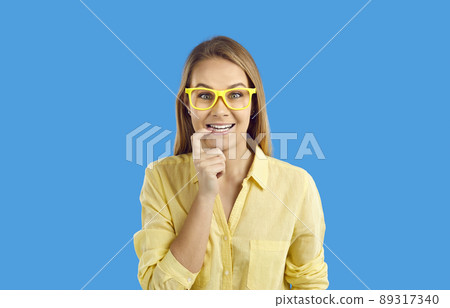 Portrait of happy funny curious student girl in glasses on blue studio background Portrait of happy funny curious student girl in glasses on blue studio background 89317340