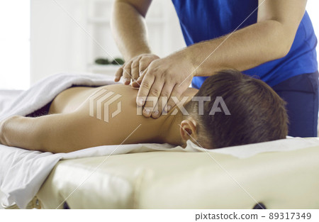 Masseur in modern health center performs therapeutic body massage for young man. Masseur in modern health center performs therapeutic body massage for young man. 89317349